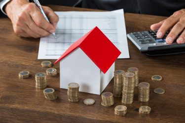 Cropped,Image,Of,Businessman,Calculating,Tax,By,Model,House,And