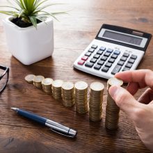 Close-up,Of,A,Person,Hand,Calculating,On,Wooden,Desk,In