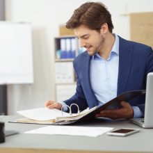 Young,Businessman,Working,With,Documents,Looking,Through,Papers,In,Folder,